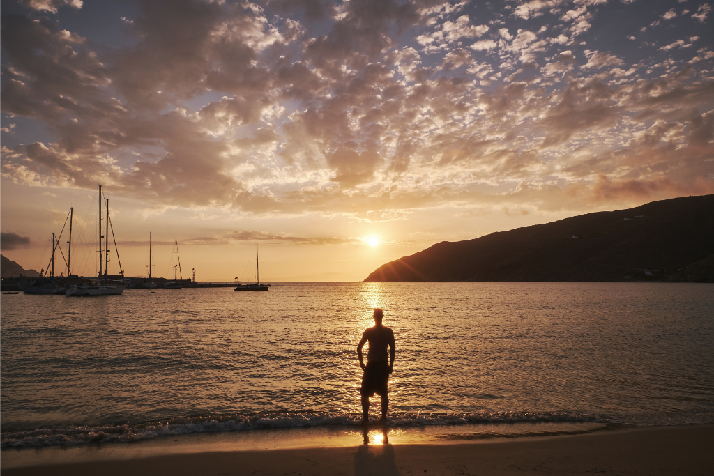 Image of a person standing on a beach in dubai with yacht in background